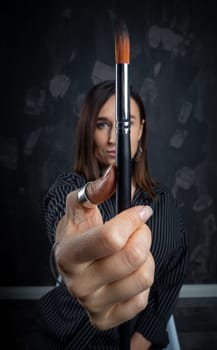 Portrait of a female artist, with brushes in her hands.
 Photo shoot on a black background in the studio