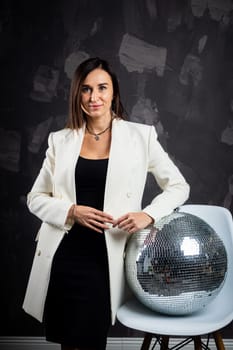 Portrait of a woman holding a silver disco ball. Taken in a photo studio. The concept of the party.