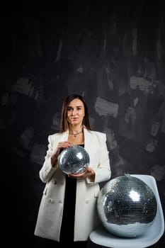 Portrait of a woman holding a silver disco ball. Taken in a photo studio. The concept of the party.