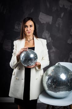 Portrait of a woman holding a silver disco ball. Taken in a photo studio. The concept of the party.