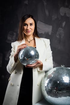 Portrait of a woman holding a silver disco ball. Taken in a photo studio. The concept of the party.