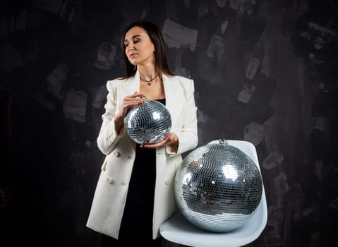 Portrait of a woman holding a silver disco ball. Taken in a photo studio. The concept of the party.