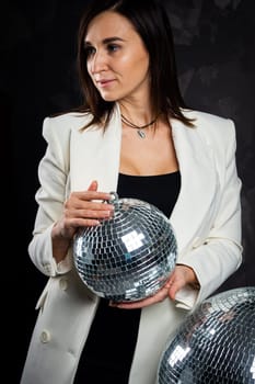 Portrait of a woman holding a silver disco ball. Taken in a photo studio. The concept of the party.