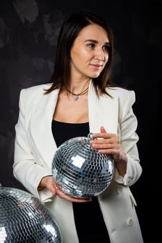 Portrait of a woman holding a silver disco ball. Taken in a photo studio. The concept of the party.