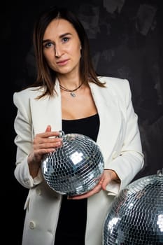 Portrait of a woman holding a silver disco ball. Taken in a photo studio. The concept of the party.