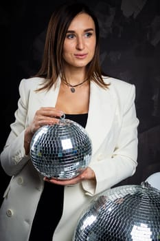 Portrait of a woman holding a silver disco ball. Taken in a photo studio. The concept of the party.