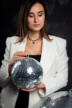 Portrait of a woman holding a silver disco ball. Taken in a photo studio. The concept of the party.