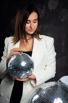 Portrait of a woman holding a silver disco ball. Taken in a photo studio. The concept of the party.