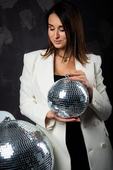 Portrait of a woman holding a silver disco ball. Taken in a photo studio. The concept of the party.