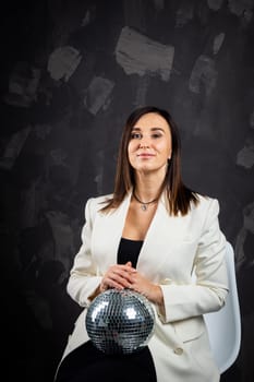 Portrait of a woman holding a silver disco ball. Taken in a photo studio. The concept of the party.