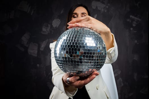 Portrait of a woman holding a silver disco ball. Taken in a photo studio. The concept of the party.