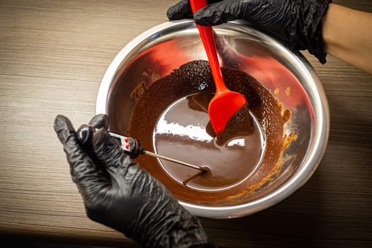 Woman cooking tasty melted chocolate on table in kitchen. Delicious dessert made of homemade chocolate.