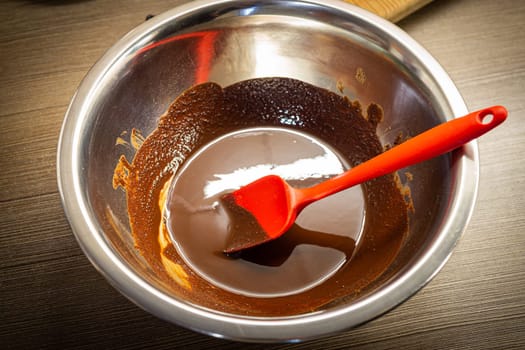 Woman cooking tasty melted chocolate on table in kitchen. Delicious dessert made of homemade chocolate.