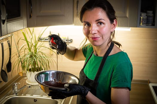 Woman cooking tasty melted chocolate on table in kitchen. Delicious dessert made of homemade chocolate.