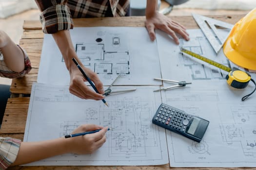 multi ethnic engineer brainstorming and measuring for cost estimating on blueprint and floor plan drawings about design architectural and engineering for houses and buildings.