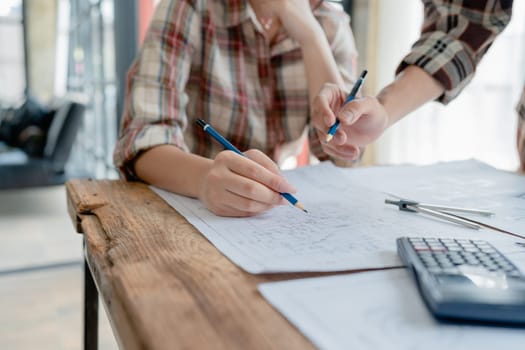 multi ethnic engineer brainstorming and measuring for cost estimating on blueprint and floor plan drawings about design architectural and engineering for houses and buildings.