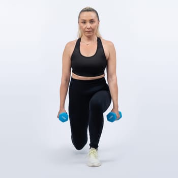 Full body length shot active and sporty senior woman lifting dumbbell during weight training workout on isolated background. Healthy active physique and body care lifestyle for pensioner. Clout