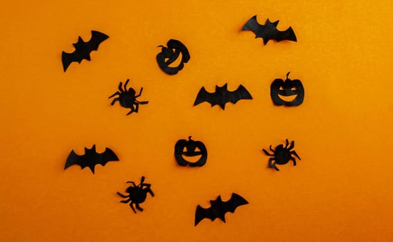 Halloween background, paper black bats, pumpkins and spiders on orange background. Background for advertising.