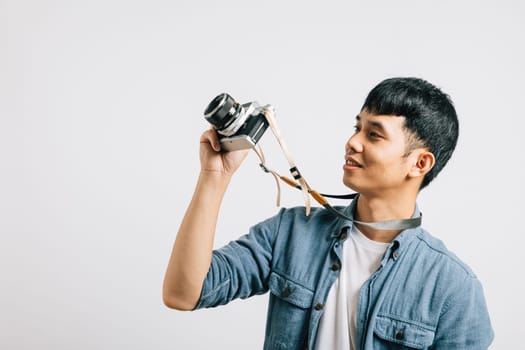 Charismatic young man smiles for a photographer with a vintage camera. Studio shot isolated on white background. This snapshot embodies the essence of glamour and fun.