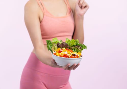 Young sporty Asian woman in sportswear holding salad bowl fill with vibrant of fruit and vegetable. Natural youthful and fit body lifestyle with balance nutrition on isolated background. Vigorous