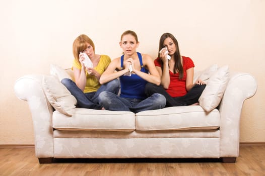 Three crying women on a sofa