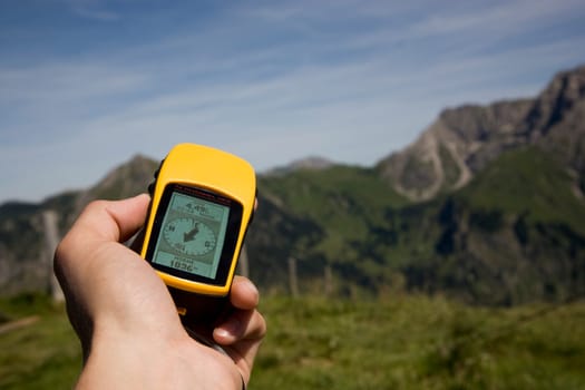 Hand holding GPS receiver and mountains in background
