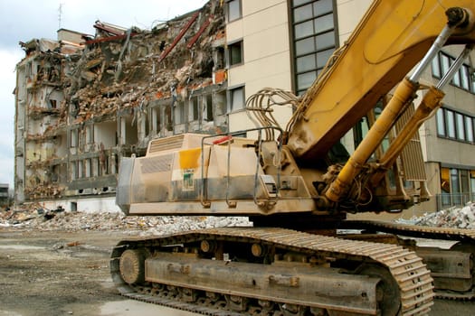 Excavator in front of demolition building