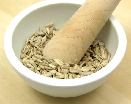 Sunflower seeds in porcelain bowl with mortar