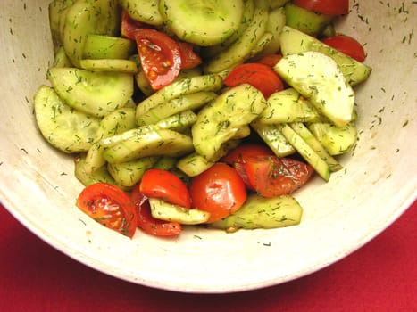 Cucumber and tomatoes with salad dressing in ceramic bowl