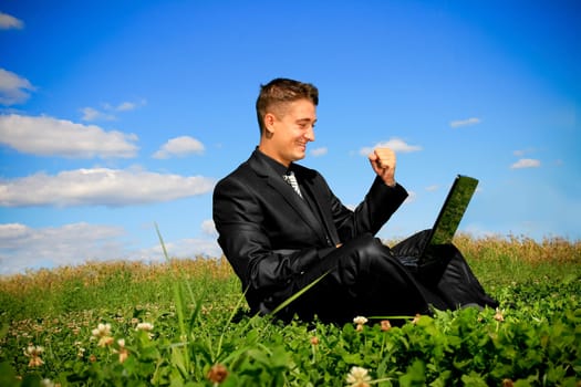 Businessman in the middle of the field on laptop