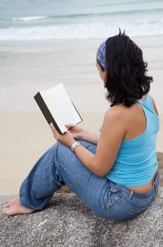 Young woman reading sitting on the beach