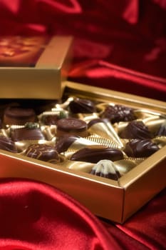Golden chocolates box on red satin