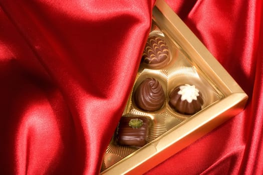 Golden chocolates box on red satin