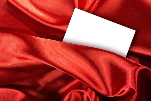 Blank white card on red colored satin