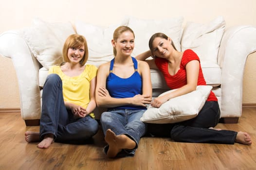Three laughing women in front of a sofa
