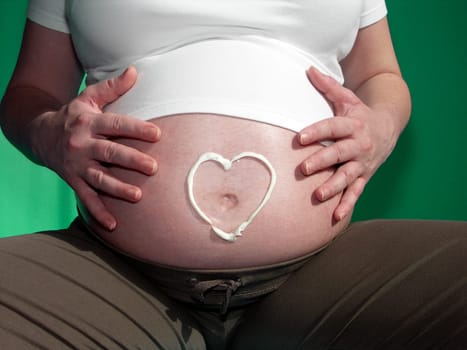 painted heart from cream on belly gravid women
