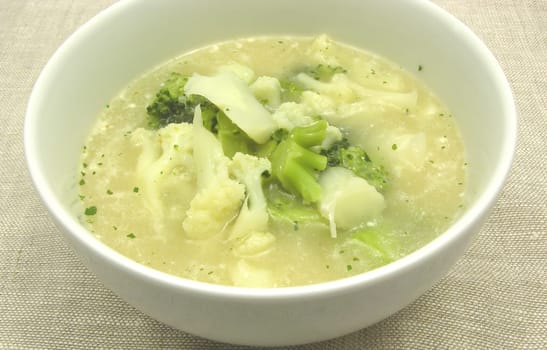 Soup with cauliflower and broccoli in porcelain bowl
