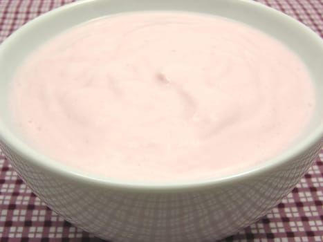 Strawberry curd in porcelain bowl on checkered cloth