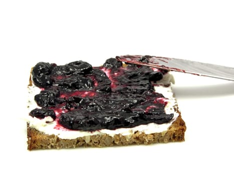 Bread with butter and blueberry jam on plate with knife