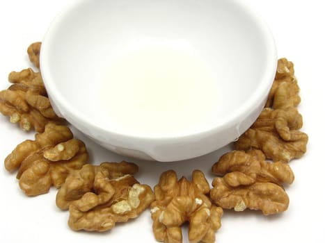 Walnut oil in porcelain bowl surrounded by walnuts