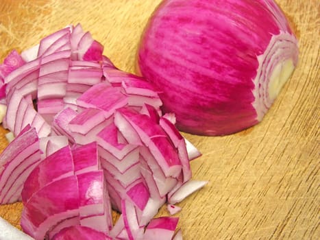 Red onion cut into cubes on wooden board