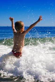 young child playing in the waves