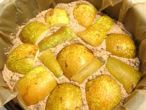 Dough of a whole wheat cake with pears in a baking pan