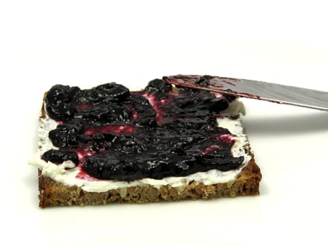 Bread with butter and blueberry jam on plate with knife
