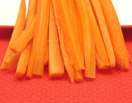 Carrots sliced on a white plate and red placemat