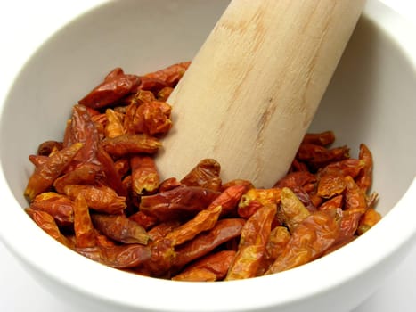 Dried red chili peppers in porcelain bowl with mortar