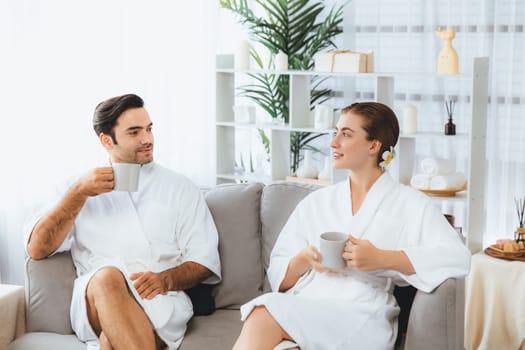 Beauty or body treatment spa salon vacation lifestyle concept with couple wearing bathrobe relaxing with drinks in luxurious hotel spa or resort room. Vacation and leisure relaxation. Quiescent