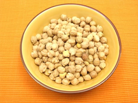 A ceramic bowl with chickpeas on an orange background