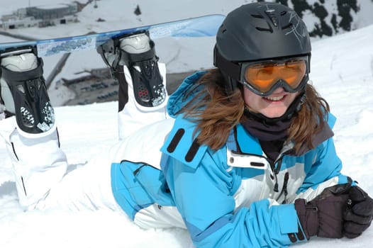Girl with snowboard lying in the snow