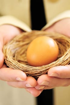 Hands holding nest with egg